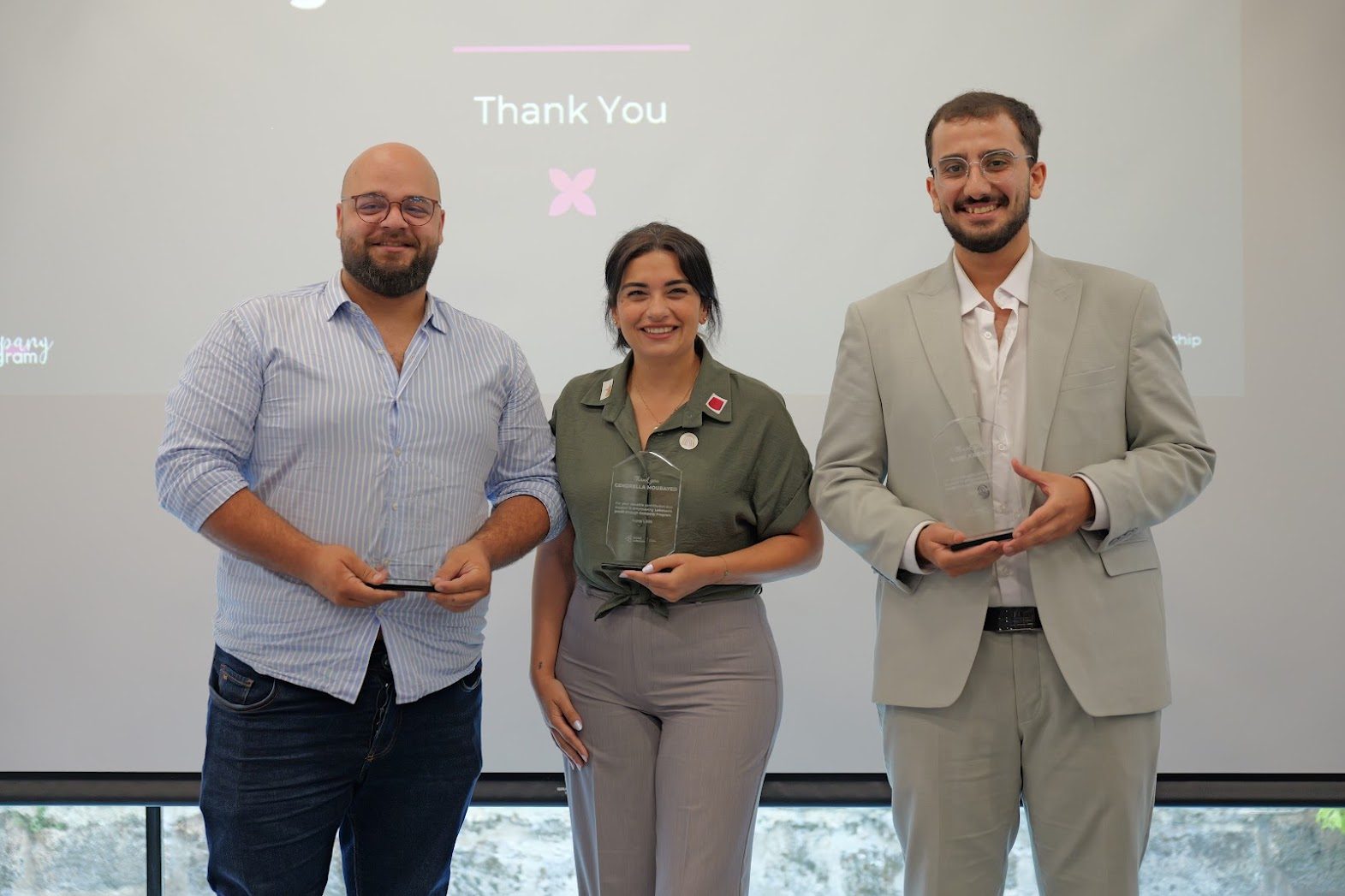 Rami Kronbi on stage at the INJAZ Lebanon final with two others, each holding an award plaque.